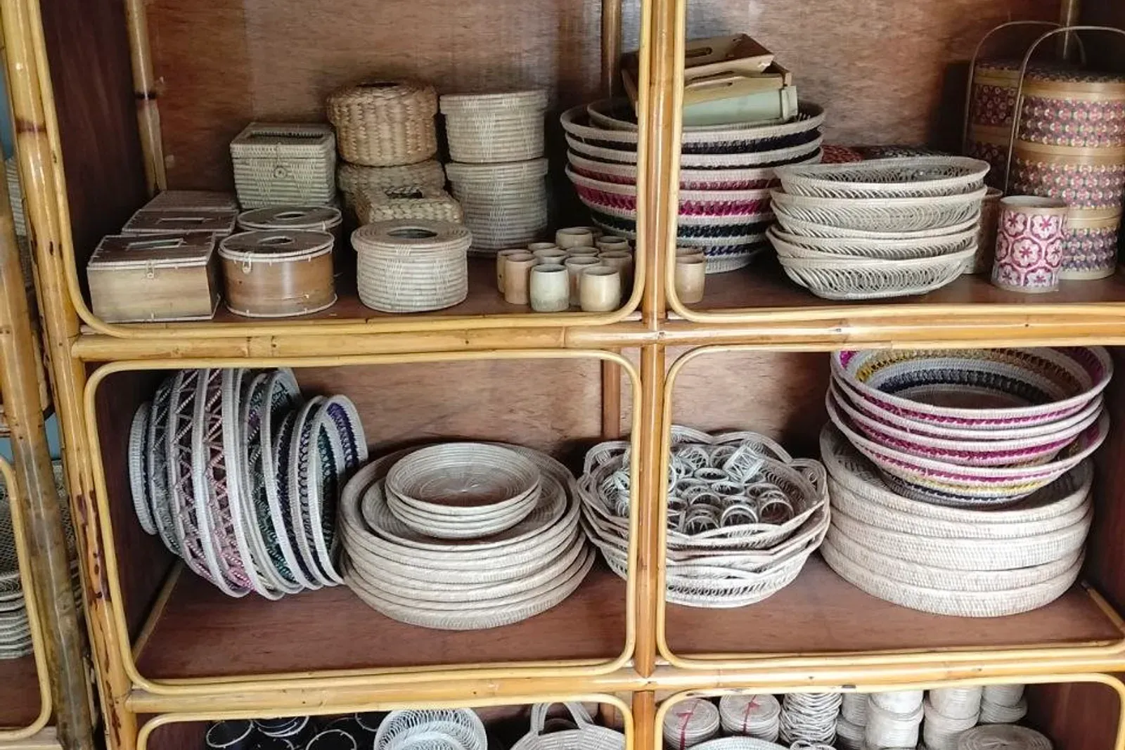 Cabinet shelves with small woven boxes, cups and patterned trays