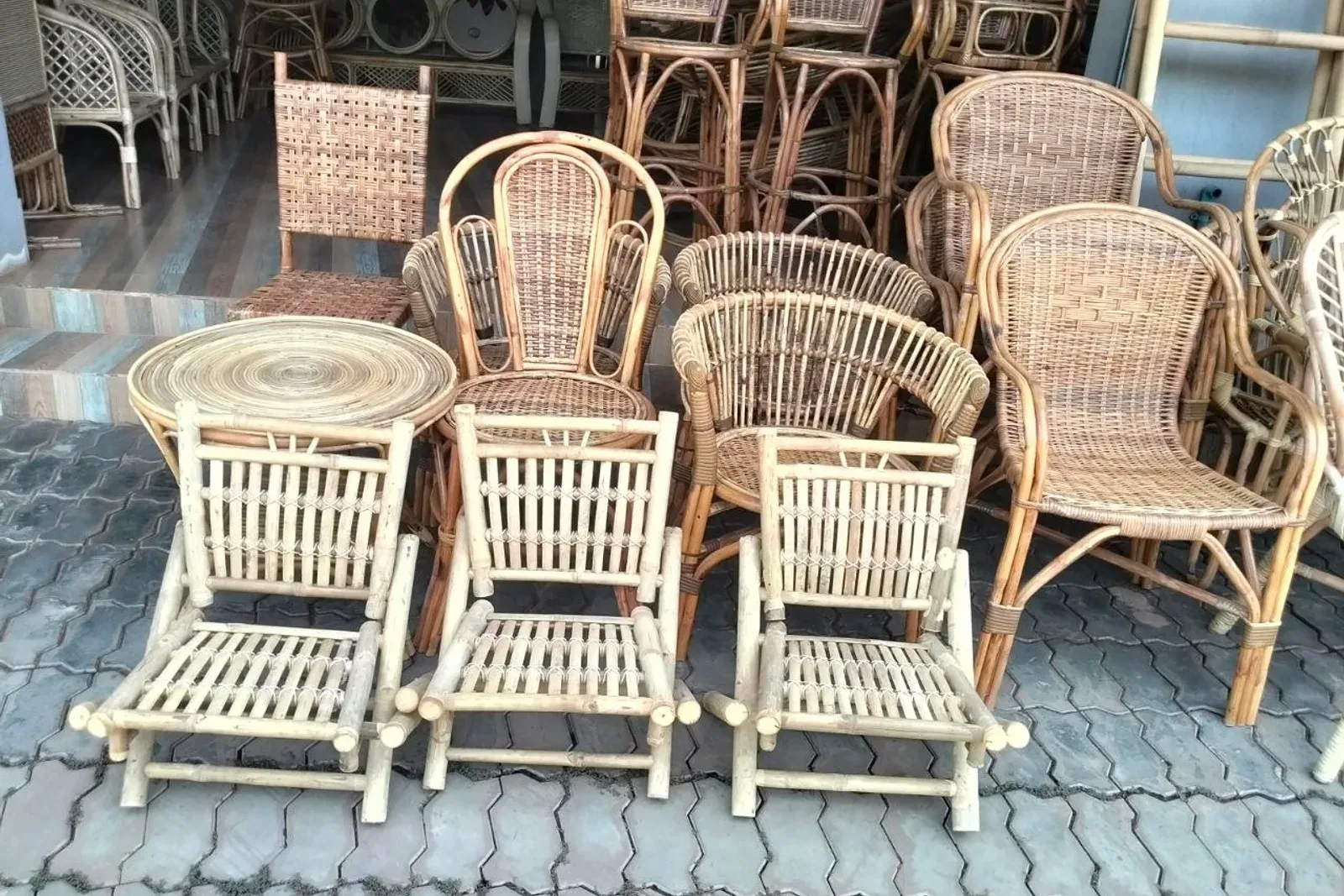 Rattan armchairs, a woven stool and bamboo folding chairs on the shop floor