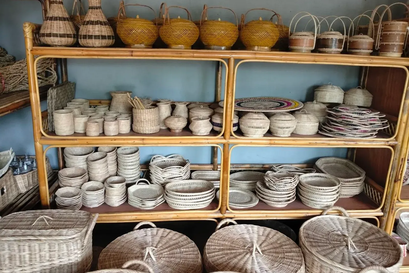 Wooden shelving unit with small woven bowls, lidded boxes and trays